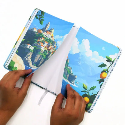 Hands opening the La Dolce Vita Vision Journal, showcasing its vibrant coastal artwork and inviting pages.