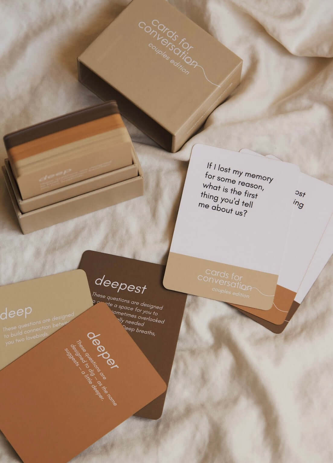 Cards for Conversation Couples Edition lying on a bed, showcasing prompt cards for deep and meaningful discussions.